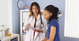 African American patient explaining issues to Asian doctor using tablet. Surgeons for Targeted Treatments