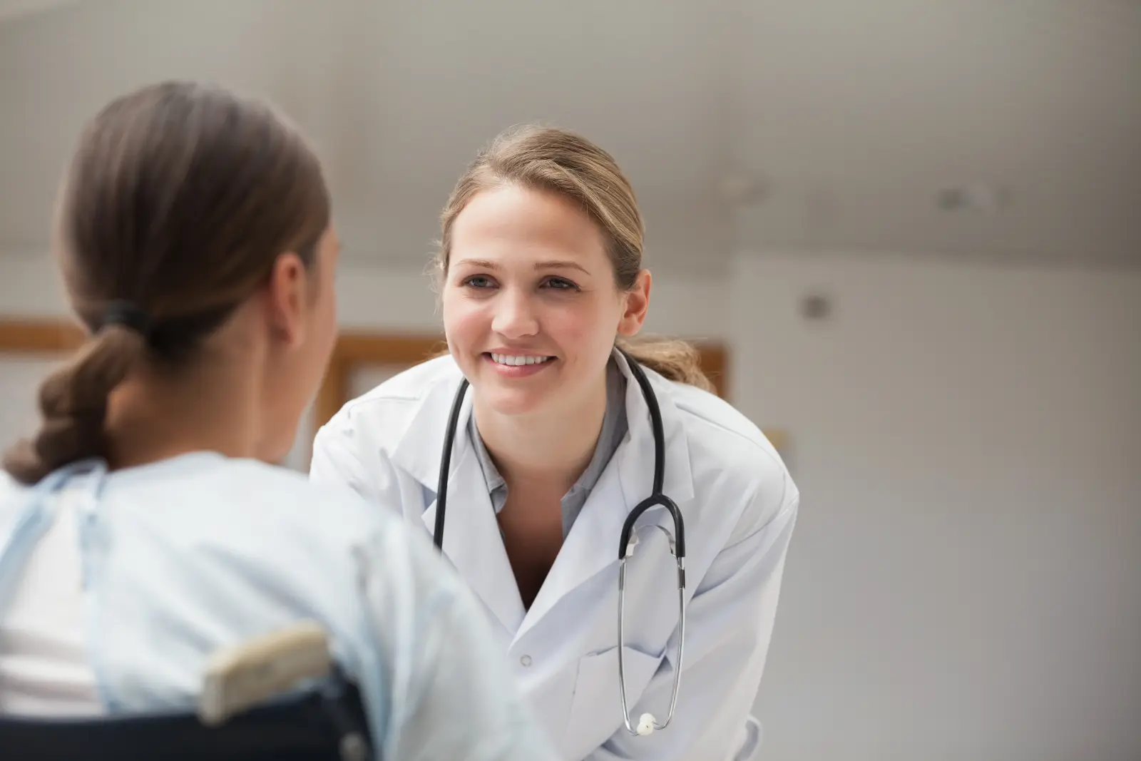 Personalized Cost-Conscious Surgery. Smiling doctor looking at a patient on a wheelchair